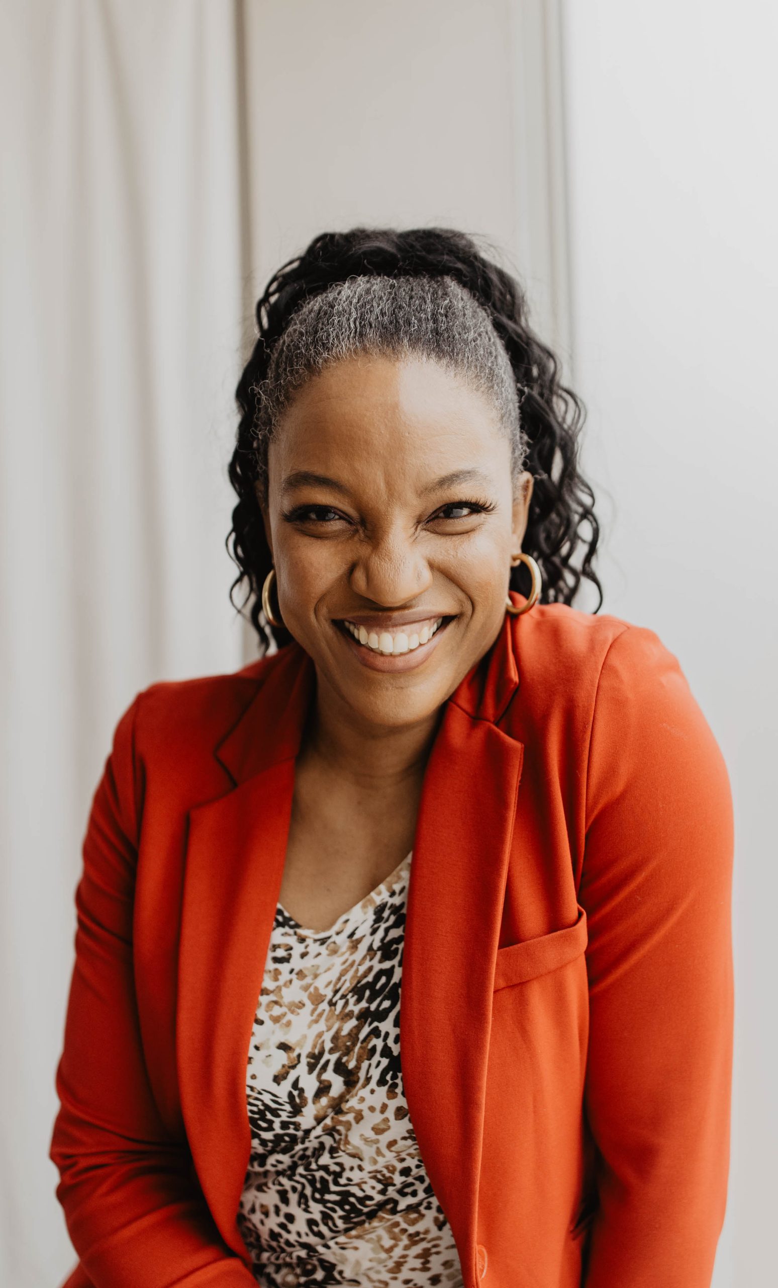Natalie Bell, smiling, in a red blazer